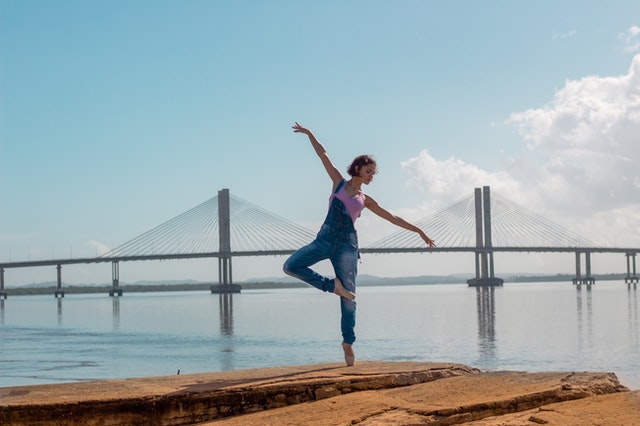 Woman dancing in front of bridge and bay