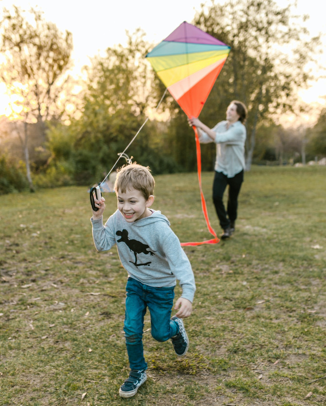 Young child running and flying a kite.