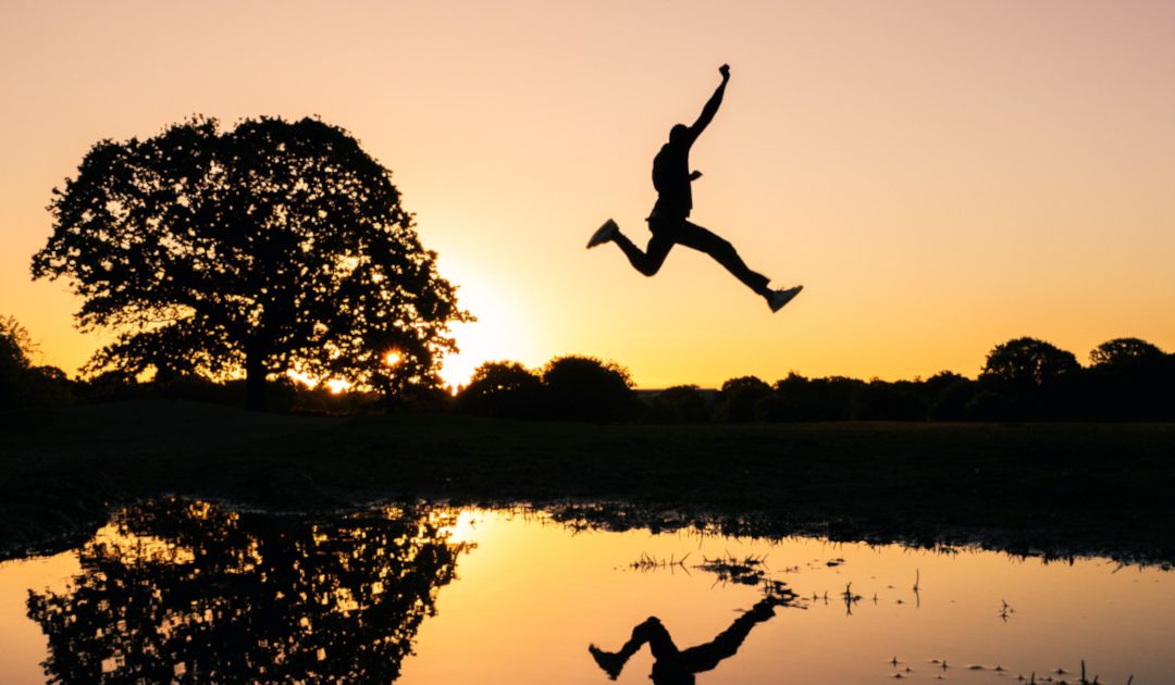 Jumping over a pond as the sun rises.