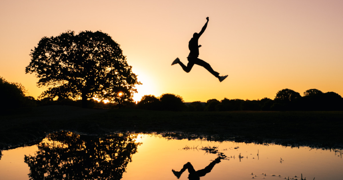 Jumping over a pond as the sun rises.